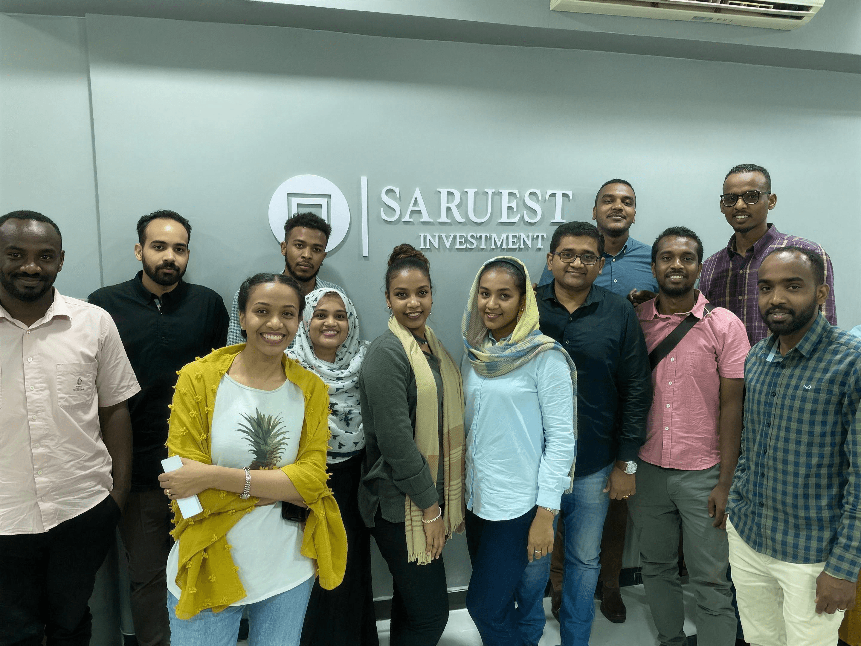 The Saruest team standing in front of the Saruest Investment sign at the Khartoum office